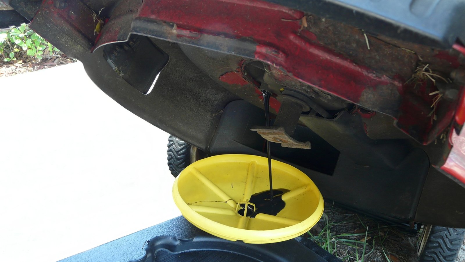 A yellow funnel positioned beneath a vehicle or machine to catch oil or liquid during maintenance.